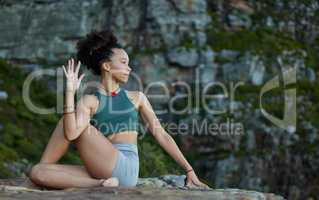 I can bend, twist and stay calm in chaos. Shot of a young woman practicing yoga while out in the mountains.