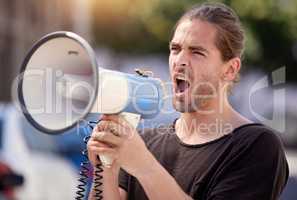 Working toward my goal. Shot of a young man using a megaphone at a protest rally.