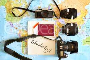 Never travel without your favourite camera. High angle shot of a map with a passport and various cameras and lenses arranged on it.