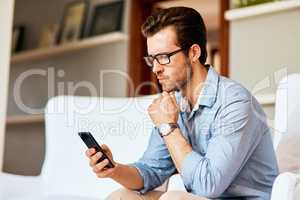 Maybe its time to switch to a new network.... Shot of a handsome young man looking confused while using a cellphone at home.