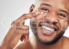 This lightweight formulation soaks right into my skin. Studio shot of a handsome young man applying moisturiser to his face against a white background.
