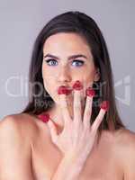 So berry nice. Studio portrait of an attractive young woman eating raspberries off her fingertips against a purple background.