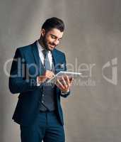 Tapped into the latest corporate trends. Studio shot of a stylishly dressed young businessman using a digital tablet against a grey background.