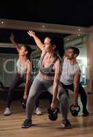 Getting in a full body workout. Full length shot of three young athletes working out with kettle bells in the gym.