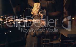 To make art, youve got to make a spark. Shot of a man using an angle grinder while working at a foundry.