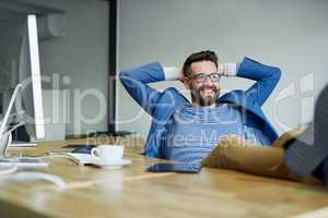 What a productive day its been. Shot of a young businessman taking a break with his feet up on the desk in an office.