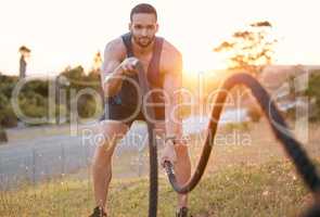 Work those muscles. Shot of a sporty young man doing heavy rope training outside.