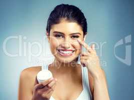 Live your healthy life. Studio portrait of an attractive young woman applying moisturiser to her face.