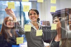 The best place to jot down ideas. Cropped shot of a group of businesswomen brainstorming on a glass wall in an office.