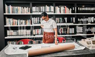 These demand her full attention. Cropped shot of an attractive young female architect working with blueprints in a modern office.