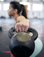 Toning muscles is all in the technique. Shot of a young woman working out with kettle bell weights in a gym.