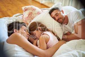 Family snuggle time. Shot of a family sleeping in bed at home.