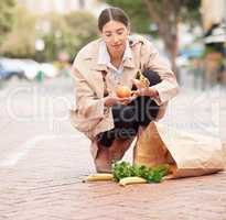 Perhaps its time for a car. Shot of a young woman looking overwhelmed while picking up groceries from the ground.