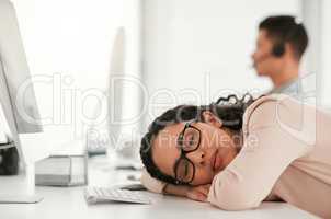 A quick nap wont hurt. Shot of a young female call center agent taking a nap at work.