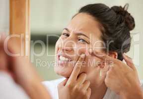 I wish I had a more permanent solution. Shot of a woman squeezing a pimple while looking into the bathroom mirror.