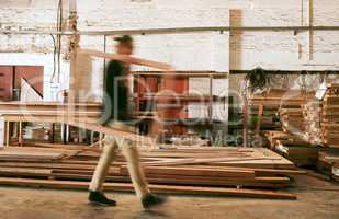 Life gets very busy around here. Defocused shot of a young carpenter working inside a workshop.