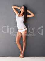 No lack of confidence. Full-length shot of a beautiful young woman posing confidently against a gray wall.