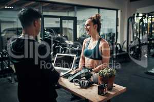 Id like to sign up for premium membership please. Cropped shot of an attractive young sportswoman talking to a male fitness instructor at the reception of a gym.