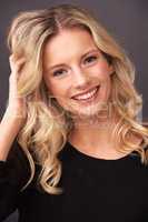 Sweet and beautiful. Portrait of a beautiful young blonde woman smiling sweetly in studio.