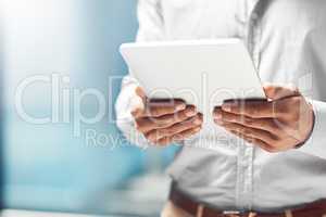 Why confine your business to a desk. Shot of an unidentifiable businessman using his tablet while standing in the office.