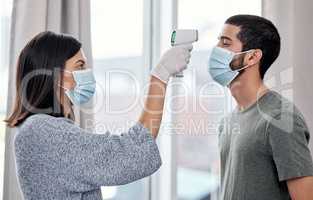 Stay one step ahead of sickness with consistent symptom management. Shot of a young woman taking her husbands temperature while recovering from an illness at home.