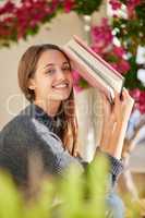 Only one thing can replace this book - another book. Portrait of a young woman reading a book at home.