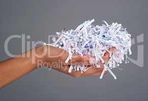 Protect your information. Studio shot of a womans hand holding a pile of shredded paper against a grey background.
