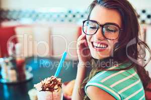 In her favourite booth. Cropped shot of an attractive young woman enjoying a milkshake in a retro diner.