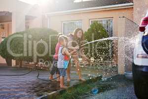 This car is going to be squeaky clean. Shot of a family washing their car in the driveway.