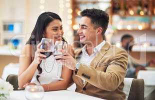 Happy anniversary babe. Cropped shot of an affectionate young couple making a celebratory toast while sitting in a restaurant.