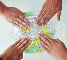 Reach out to the world. High angle shot of a group of unrecognisable people with their hands on a world globe.