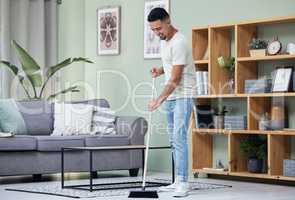 Dust doesnt stand a chance in this house. Shot of a young man sweeping the floor at home.