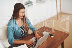 Working from the comfort of home. Shot of a focussed freelancer using her laptop while working from her office at home.