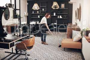 A clean space is a happy space. Shot of a hairstylist sweeping the salon.