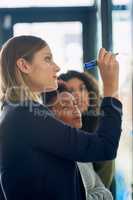 Weighing the pros and cons of their plans. Shot of a group of young entrepreneurs brainstorming with notes on a glass wall in an office.