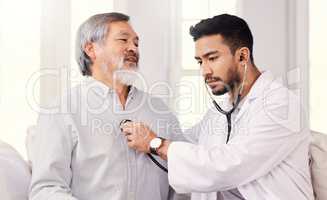 Let me take a listen. Shot of a doctor listening to a senior mans heartbeat during a checkup.