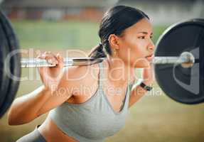 Lifting her spirits. Cropped shot of an attractive young female athlete exercising with weights outdoors.