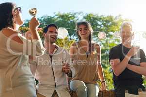 Enjoying some wine in the sunshine. Shot of a group of happy young friends hanging out at a backyard dinner party.