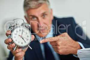 The clocks ticking. Portrait of a mature businessman gesturing toward a clock in frustration.