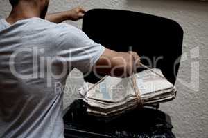 Organisation is key. Shot of a young man putting newspaper in the bin to be recycled.