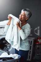 That smell of beautifully scented fabric softener. Shot of a mature woman smelling freshly washed towels while doing laundry at home.