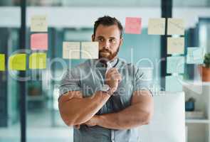 Brainstorming helps you develop creative solutions to a problem. Shot of a young businessman brainstorming with notes on a glass wall in an office.