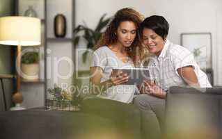 One day Ill find her. Shot of a young lesbian couple using a tablet while relaxing in their lounge at home.