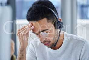 Work is piling up faster than I can handle. Shot of a young businessman suffering s headache at his desk in his office.