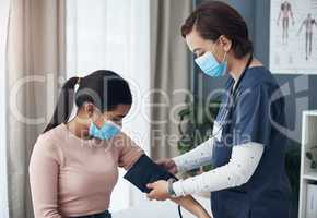 Im just going to put this around your arm. Shot of a young female doctor checking a patients blood pressure in an office.