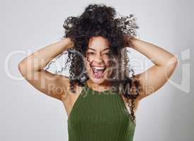 The natural hair struggle is real. Studio shot of a woman with messy hair posing against a grey background.