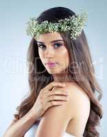 Even the flowers pale in comparison. Studio shot of a beautiful young woman wearing a floral head wreath.