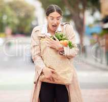 These paper bags arent always the best option. Shot of a beautiful young woman trying to hold keep her groceries from falling from a broken paper bag.