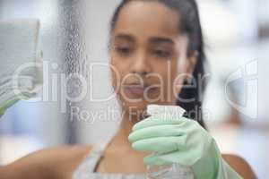 Have to get these windows clean. Shot of a young woman cleaning windows at home.