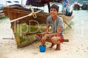 My boat is my livelihood. Portrait of a man from Thailand next to his boat at the waters edge.